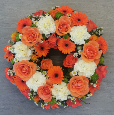 Wreath SYM-315 - A beautiful classic wreath arranged using peach and green flowers and finished with fine foliage.